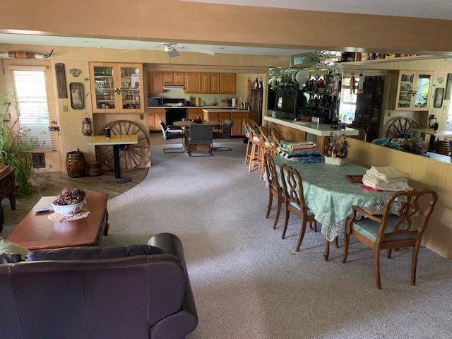 Spacious living room with dining tables, chairs, sofa, and a view into a kitchen area
