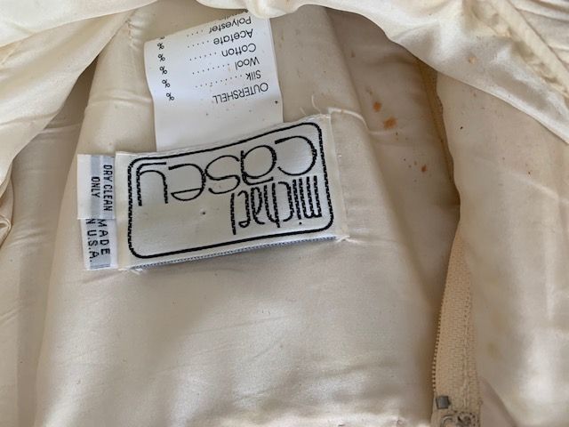 Close-up of a cream jacket lining with an upside-down Michael Cosey label and care tag