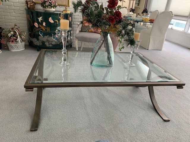 Glass coffee table with candles and a vase of flowers in a bright living room