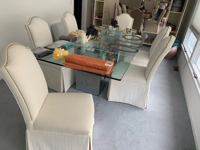 Elegant dining room with cream chairs, a glass table, and white curtains by large windows