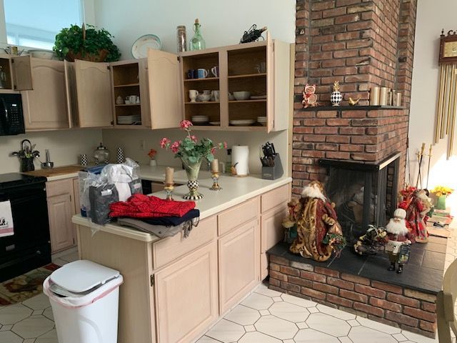 Kitchen with beige cabinets, brick fireplace, countertop decor, and flowers in a bright home interior