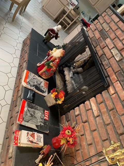 Shrine altar with flowers and offerings beside a brick fireplace indoors