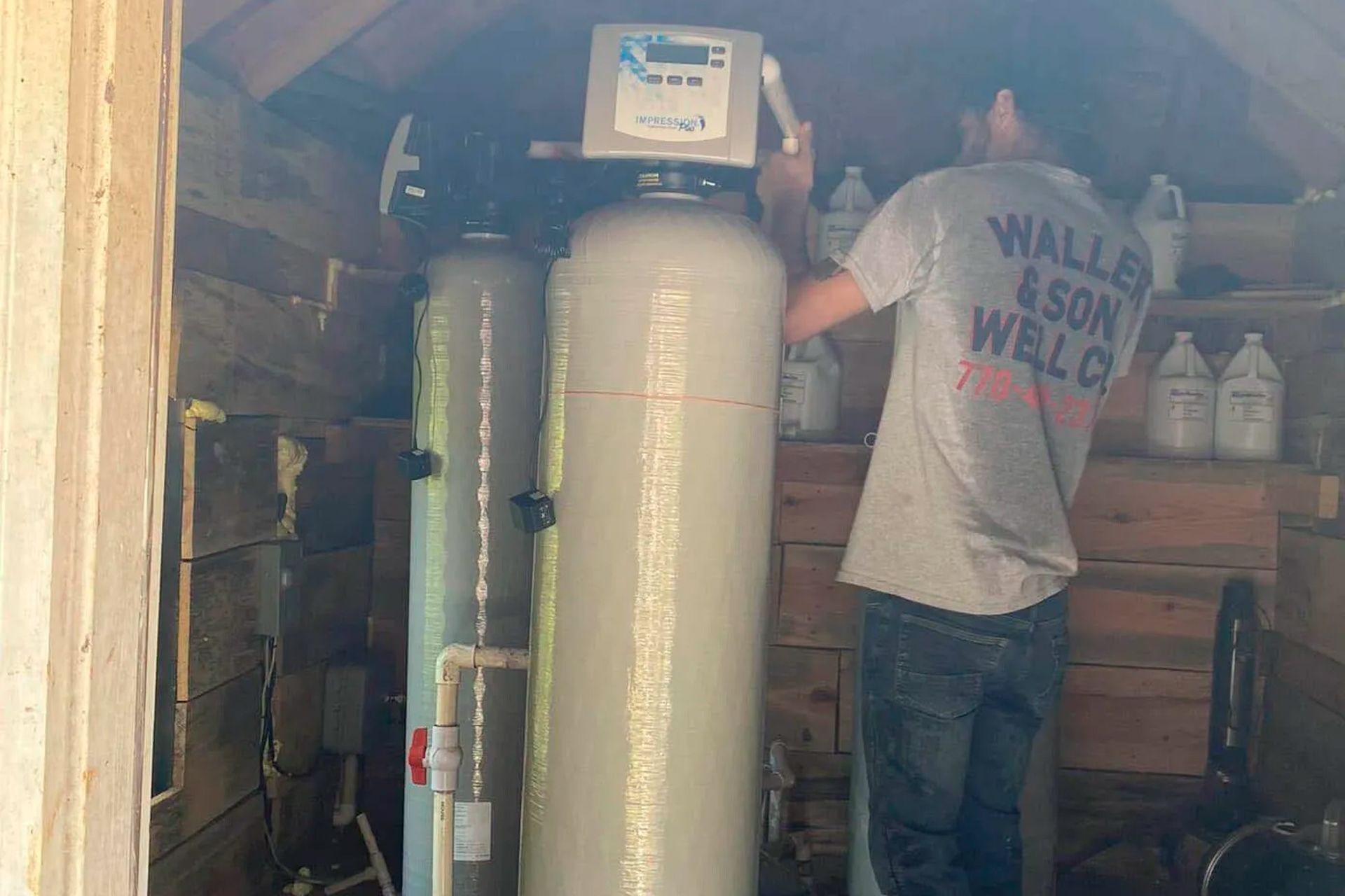 Man working on a water filtration system inside a wooden shed.