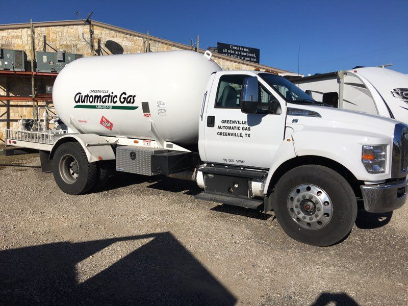 White propane delivery truck with tank, parked outdoors.