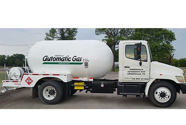 White propane delivery truck with large tank, green logo, on a road.