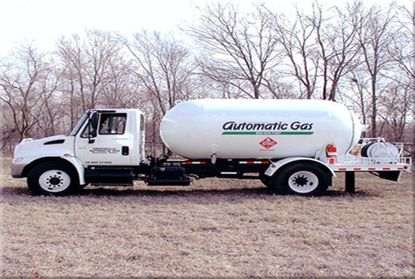 White propane delivery truck with large tank, parked on grass.