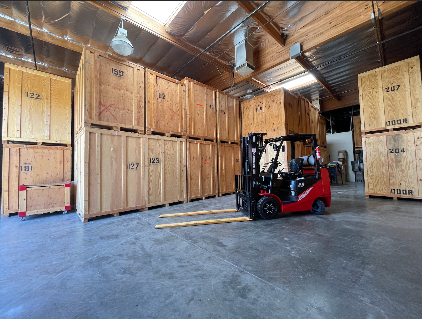 Forklift in warehouse loading wooden storage crates.