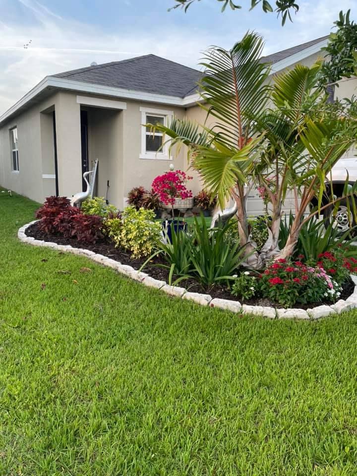 A house with a landscaped garden bed filled with colorful flowers and plants.