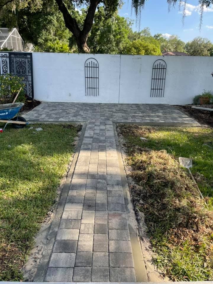 Backyard patio with gray pavers and white wall; two decorative black metal window grilles.