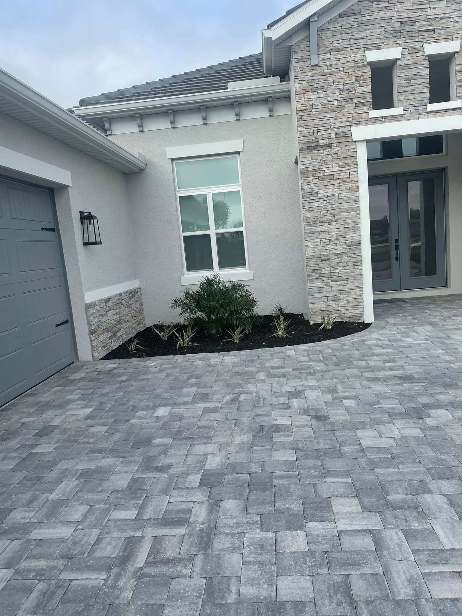Exterior view of a modern house with gray brickwork and paved driveway.
