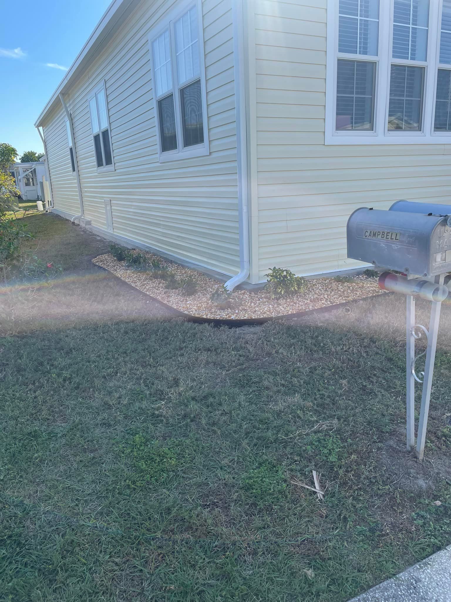 Light yellow house with mailbox on green lawn.