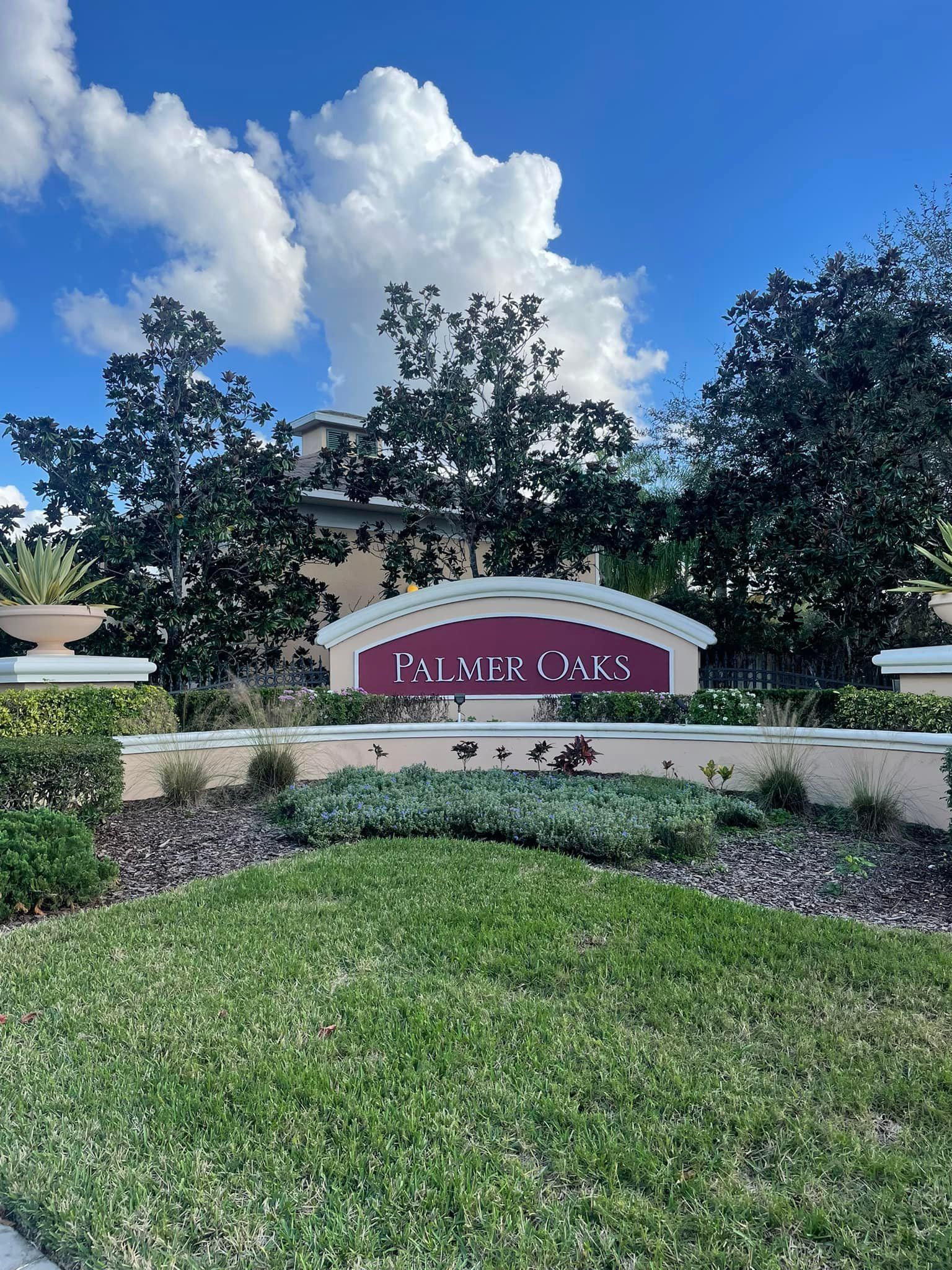Sign for Palace Oaks, surrounded by landscaping, under a partly cloudy sky.