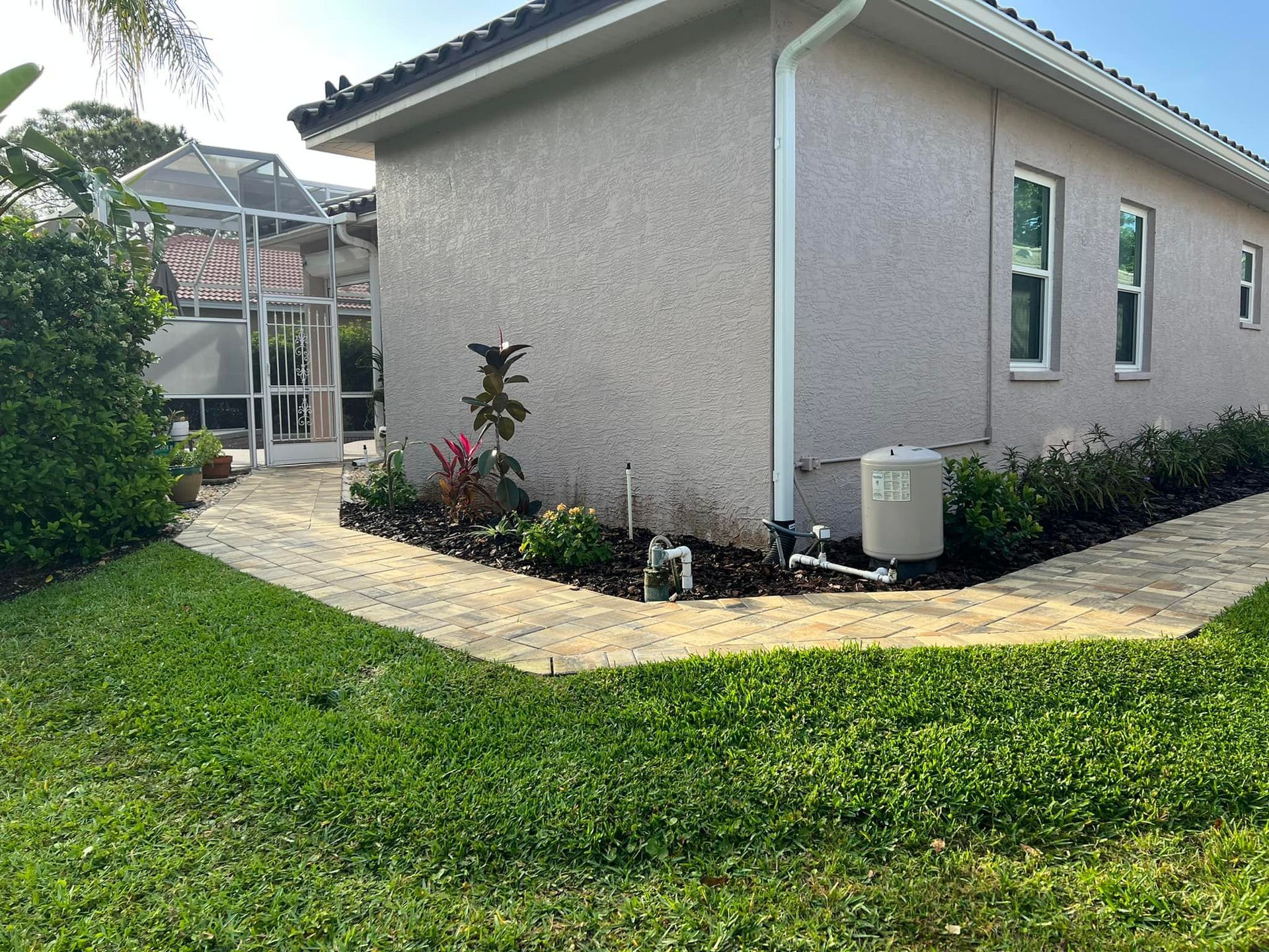 Exterior of a house with a path, landscaping, and a pool enclosure in the background.