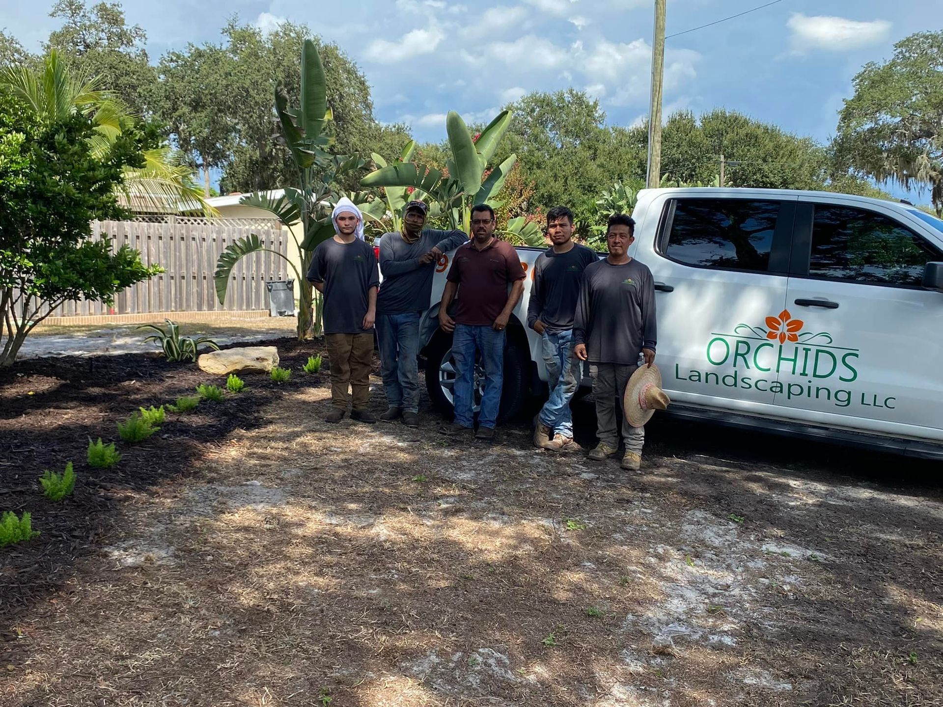 Landscaping crew posing by a white truck with 