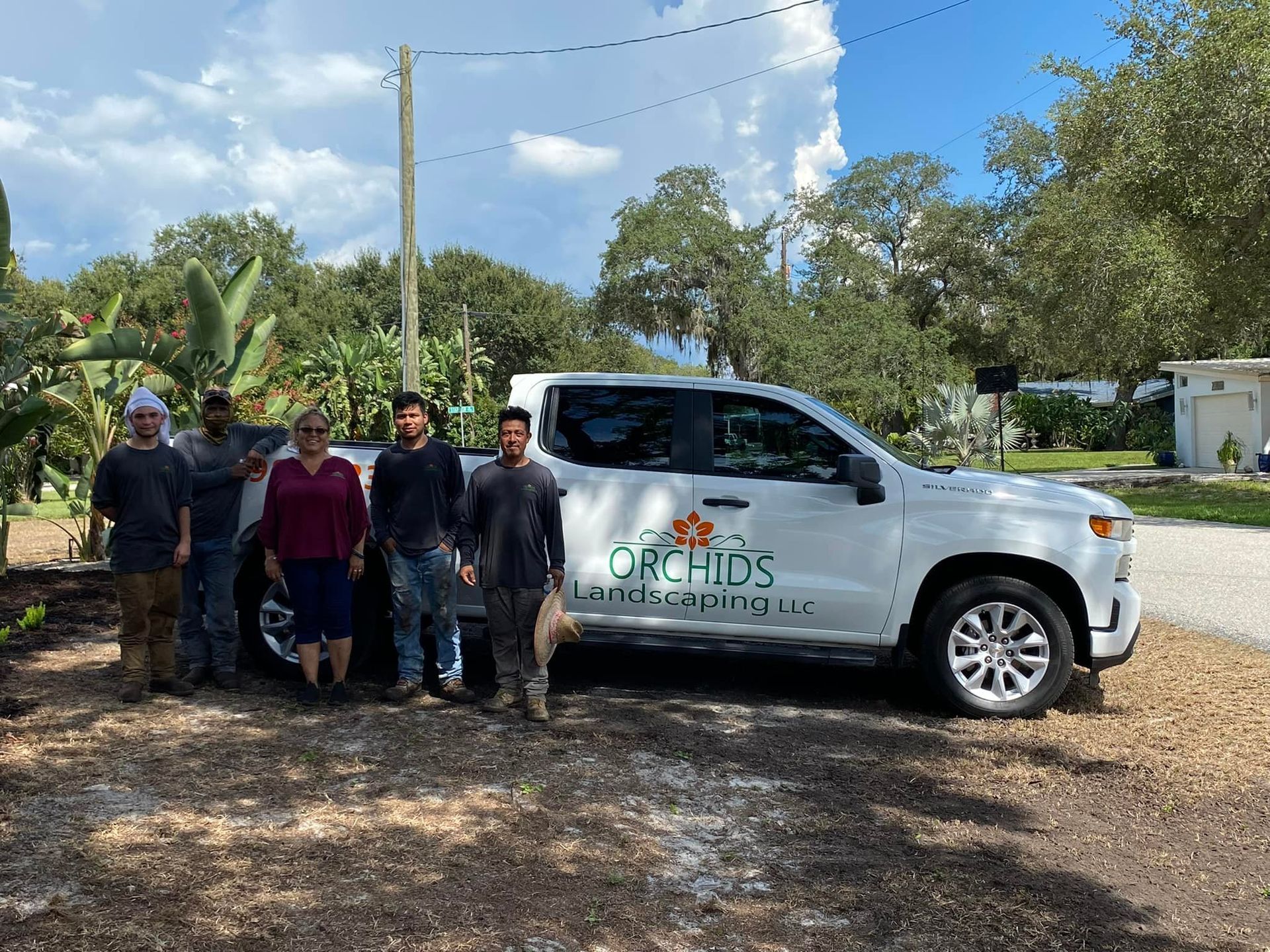 Group of people posing with a white truck labeled 