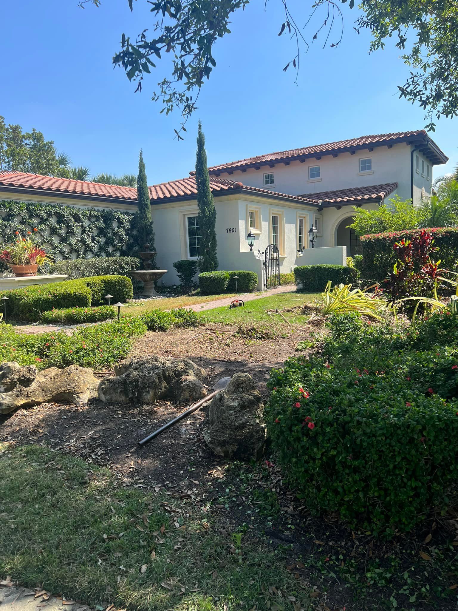 Spanish-style house with terra cotta roof, stucco walls, and lush landscaping.