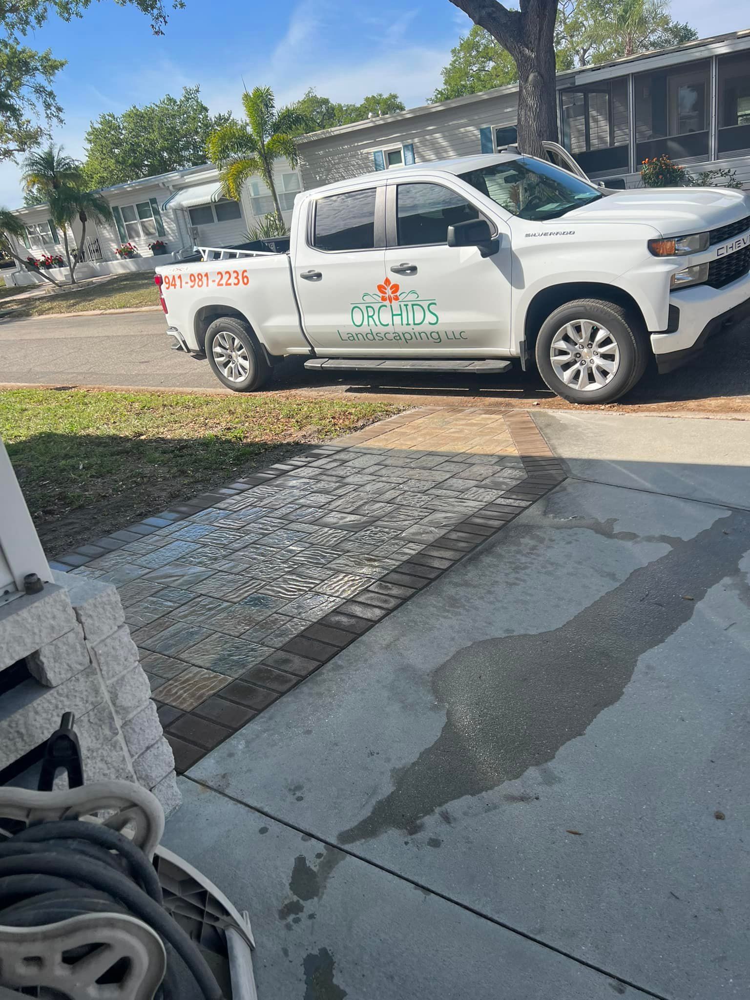 White pickup truck with company logo parked on a street near a sidewalk.