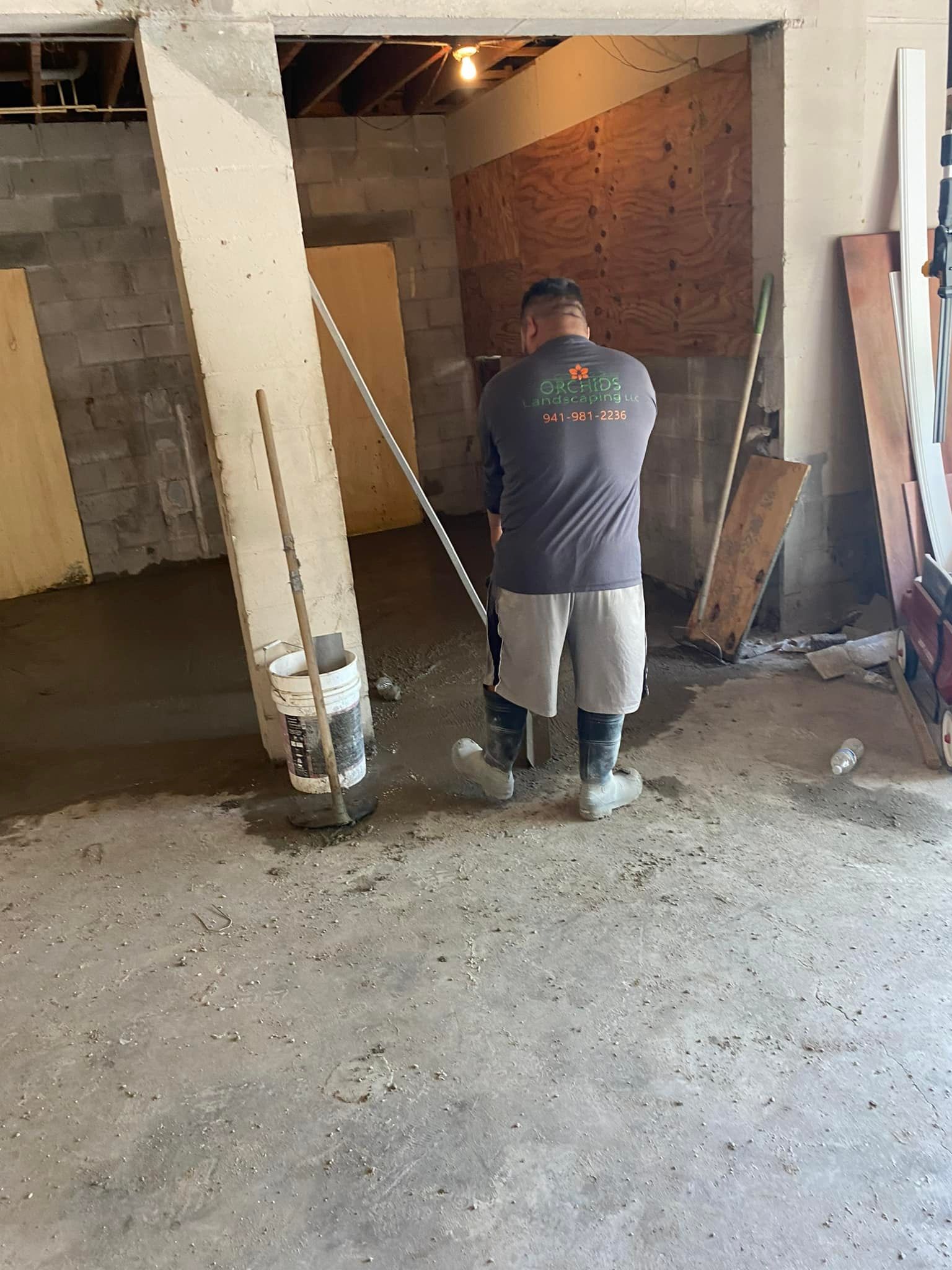 Person smoothing concrete floor with a tool in a construction area.