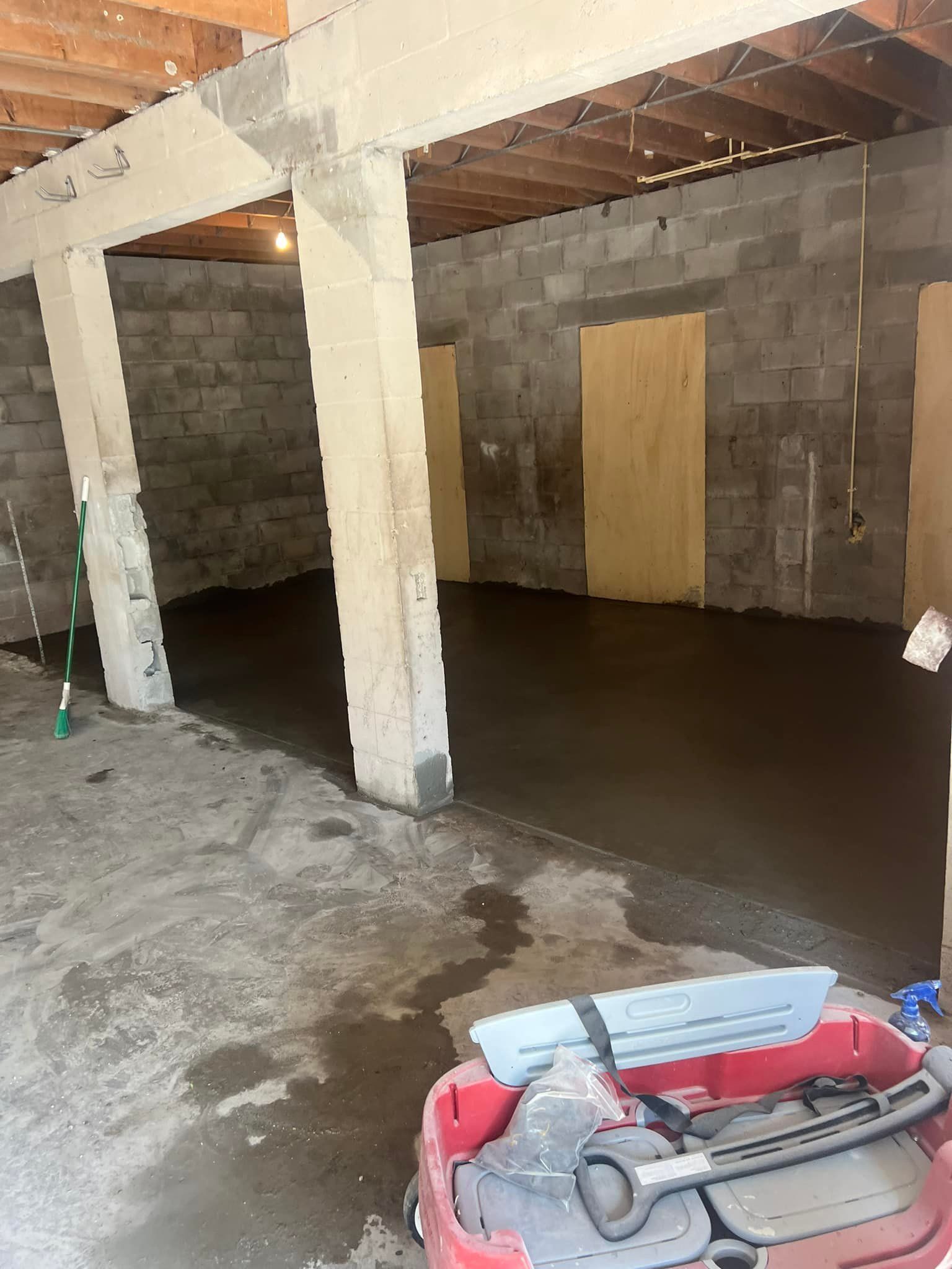 Basement with new concrete floor, cinder block walls, and support beams.