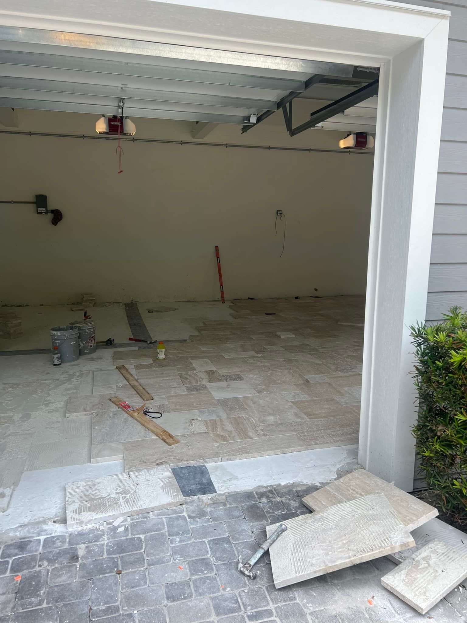Garage under renovation; entryway with removed flooring and tools visible.