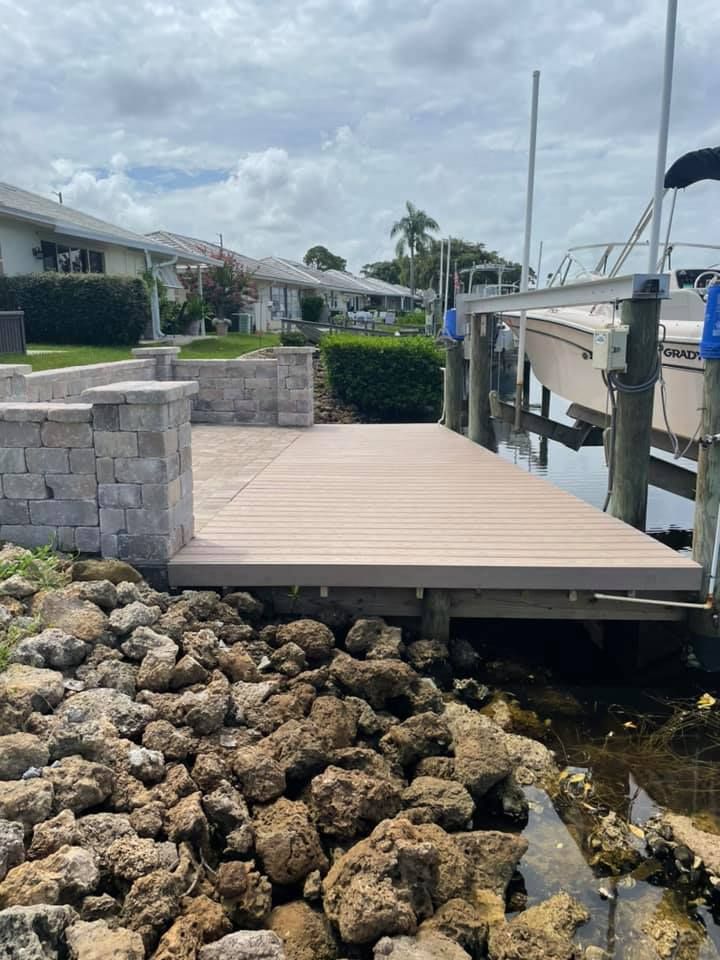 Dock with composite decking, stone retaining wall, and boat lift. Cloudy day, water and rocks in the foreground.