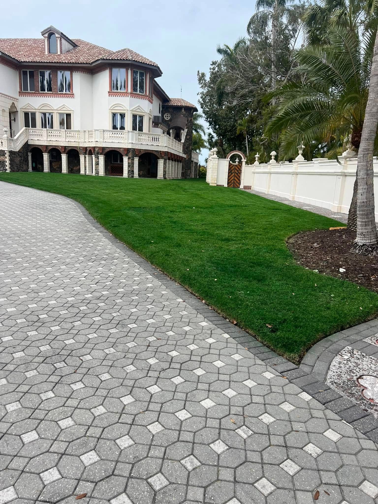 A large two-story house with a stone driveway and a green grassy slope.