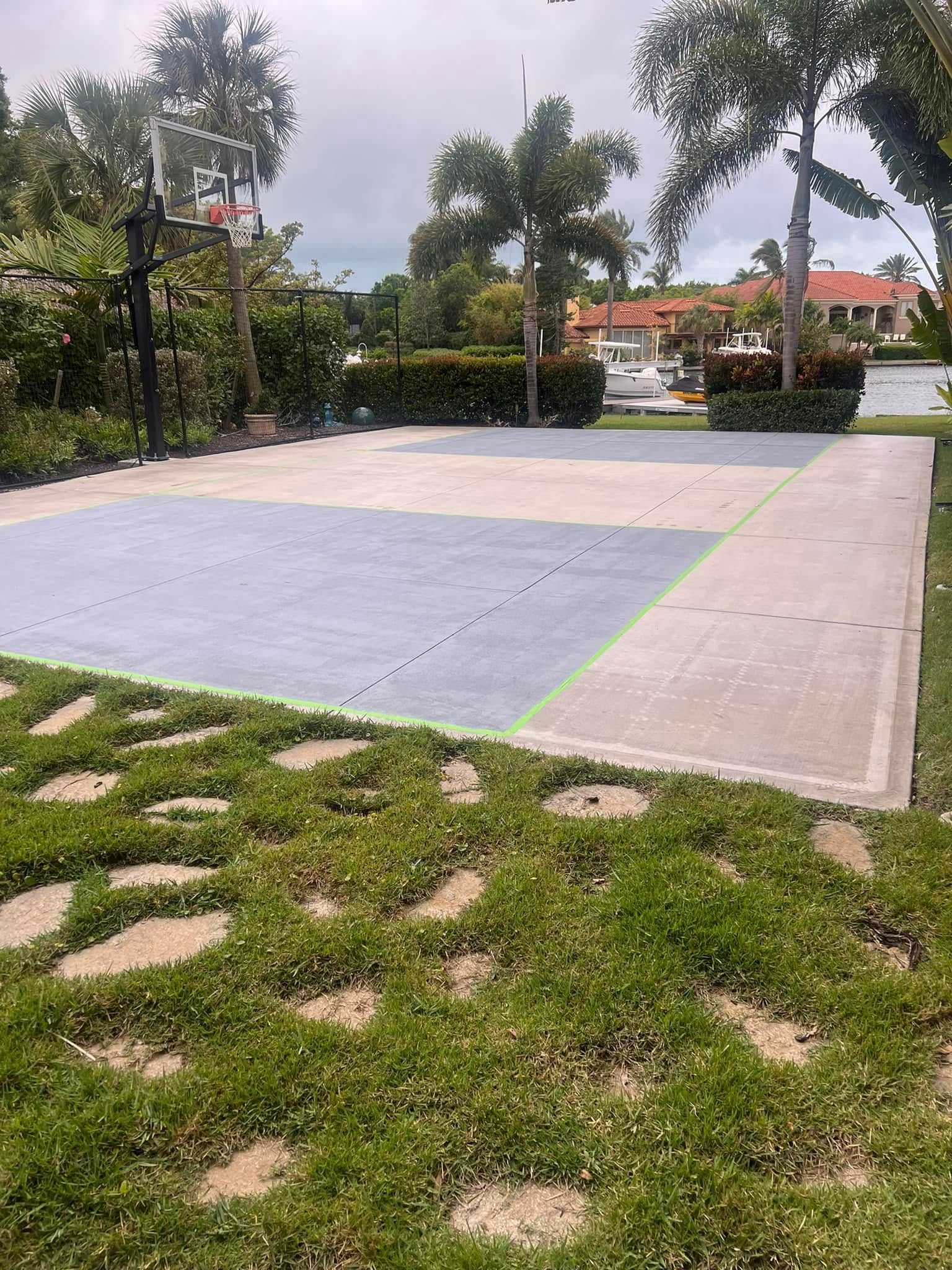 Basketball court with grass pavers, hoop, and trees.