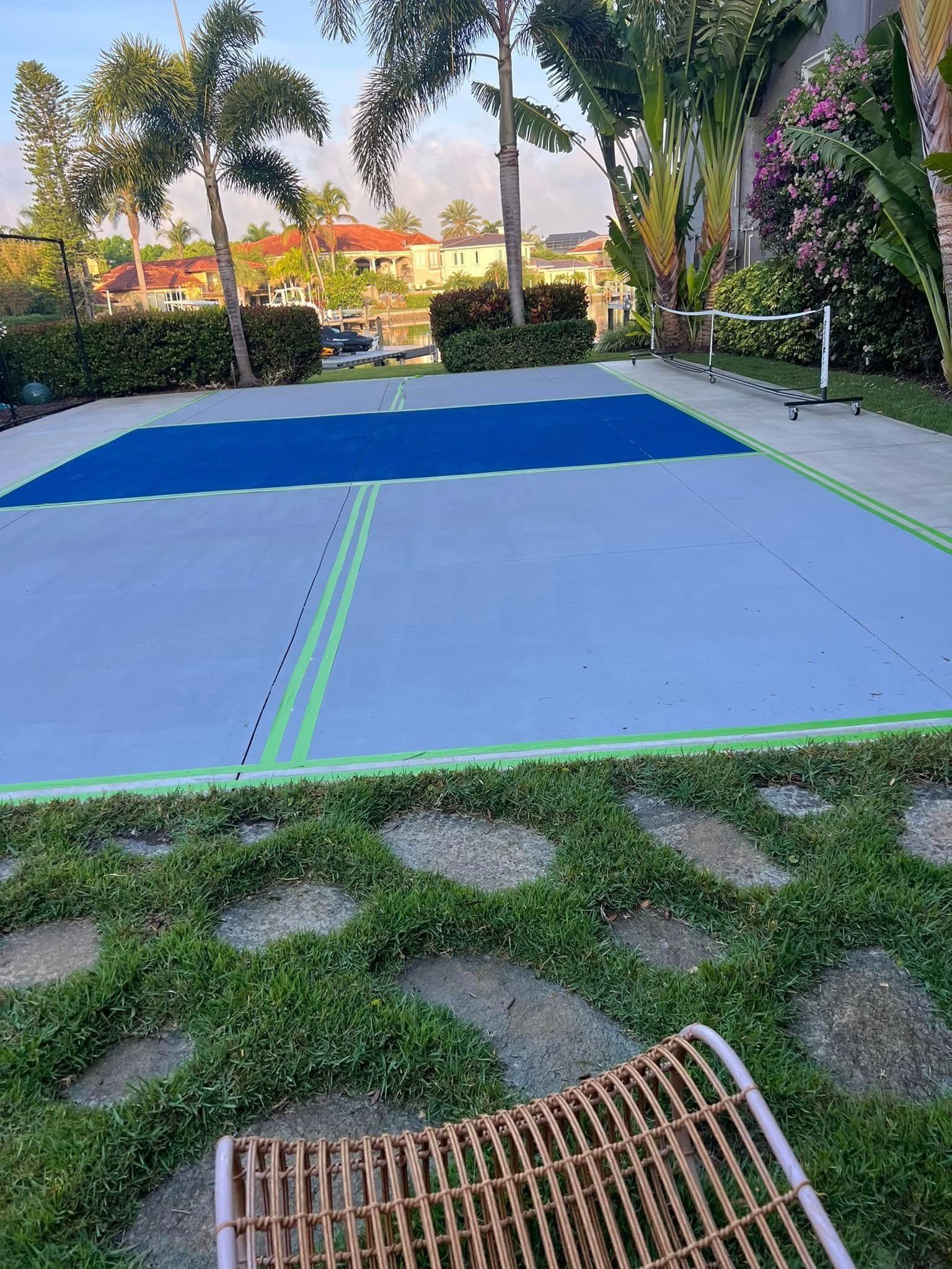 Pickleball court with blue and gray surface, green lines, set outdoors.
