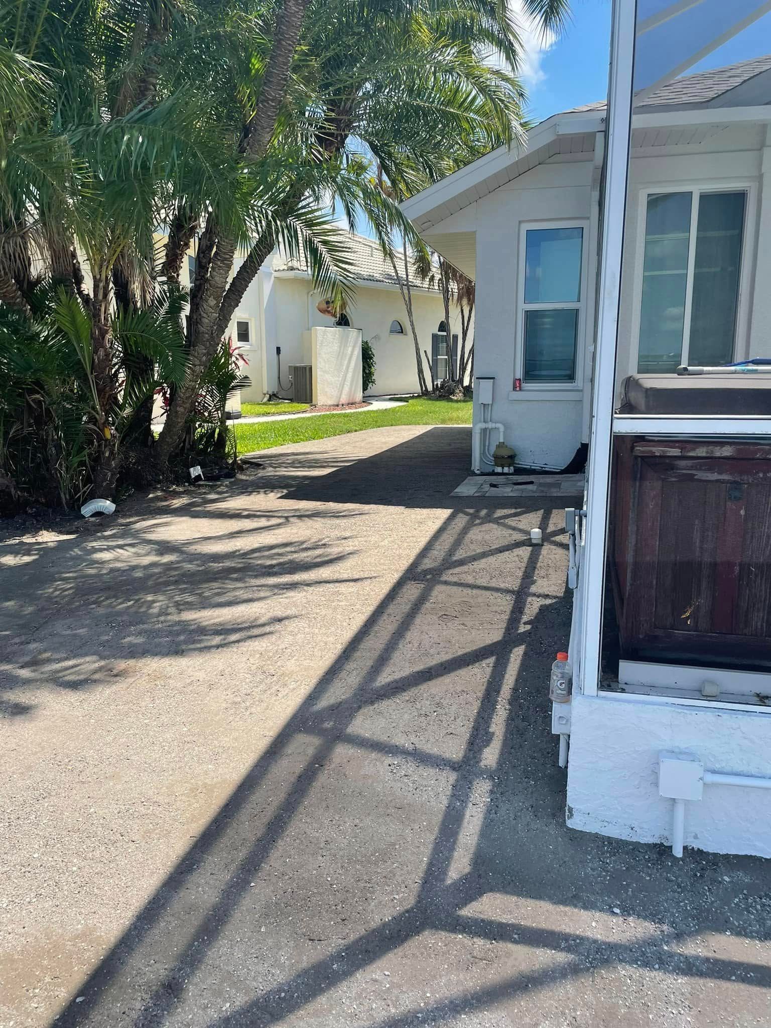 Gravel pathway leading toward white buildings with trees casting shadows.