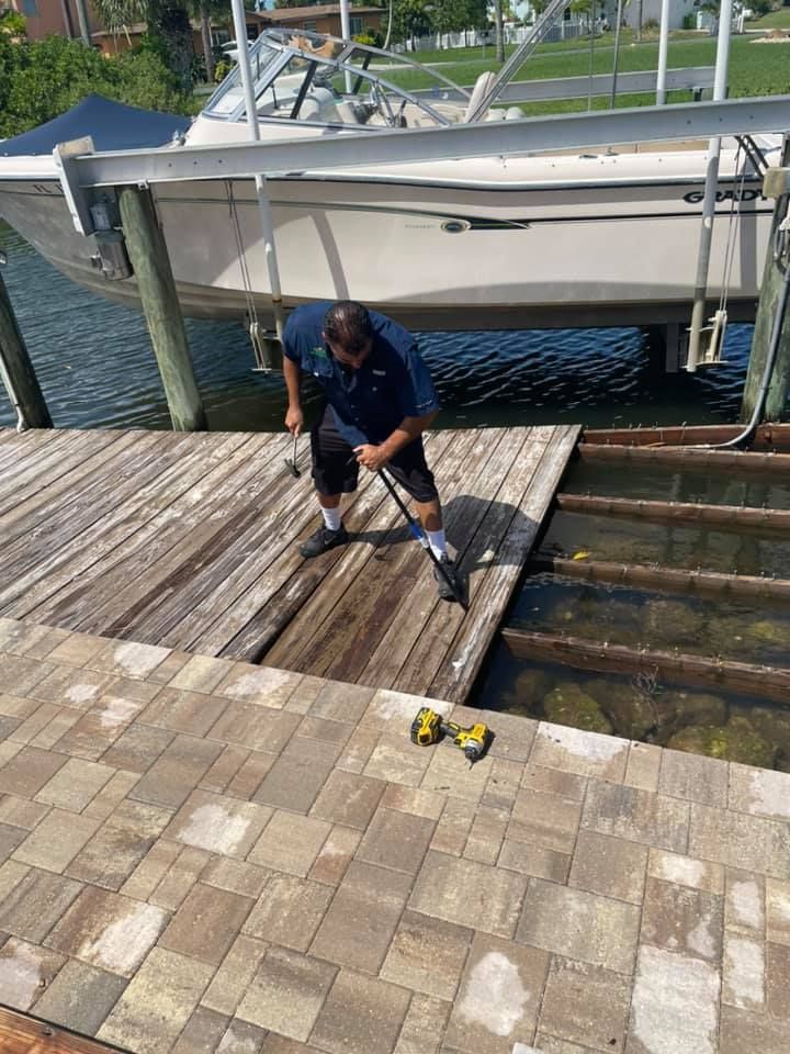 Man repairing a wooden dock by a boat lift over water. He is using tools.
