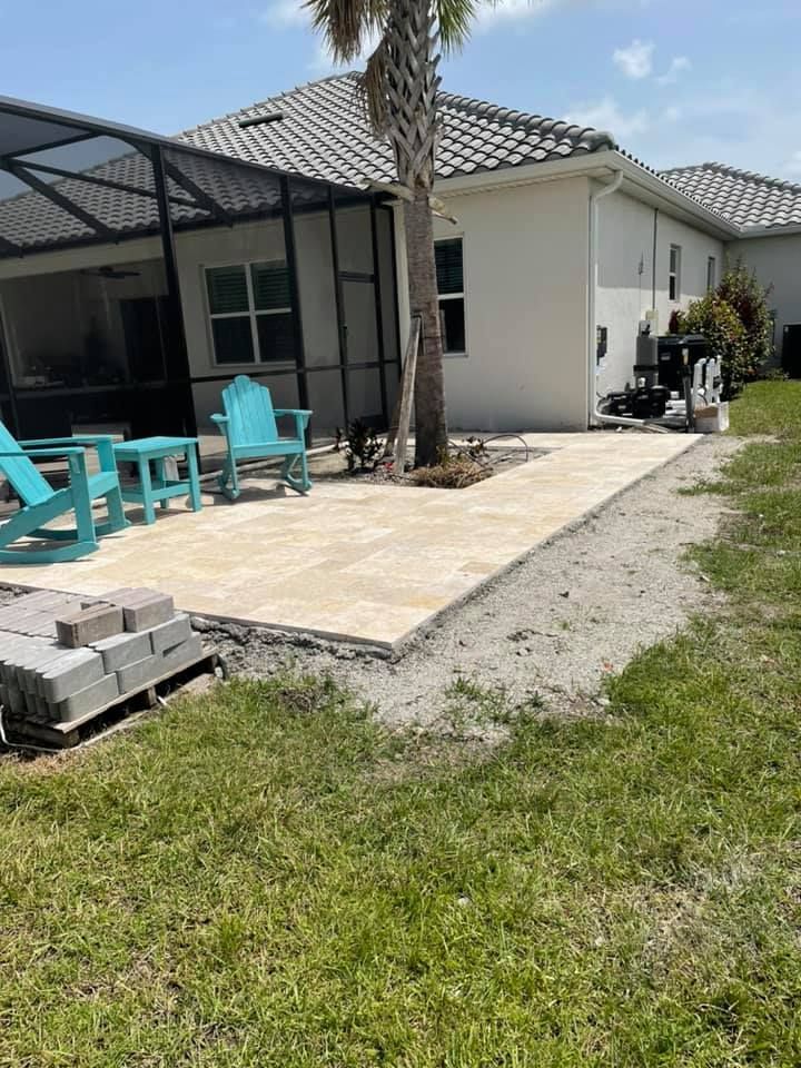 Patio with light pavers and turquoise furniture next to a grassy lawn.