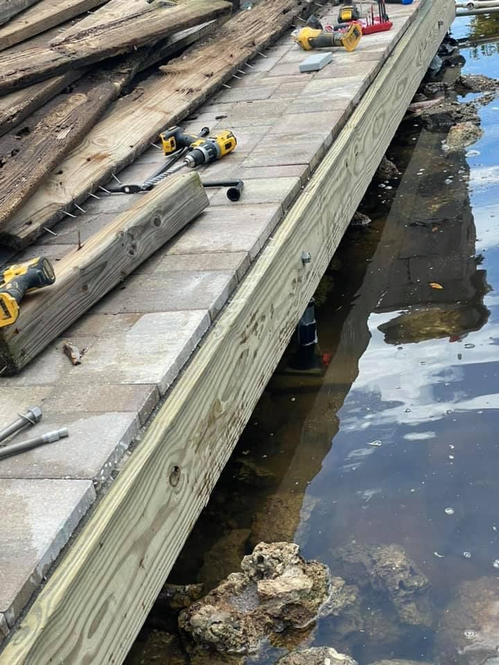 Dock repair with new wood installed along the water's edge, tools visible, old boards removed.