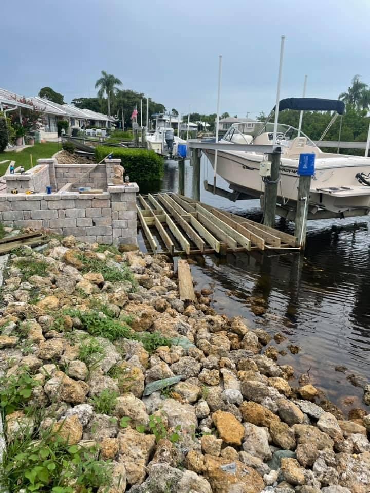 Dock under construction with boats and a rocky shoreline.