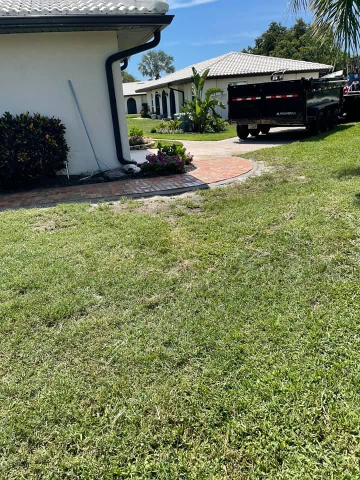 Green lawn with brick path leading to buildings; black truck parked nearby.