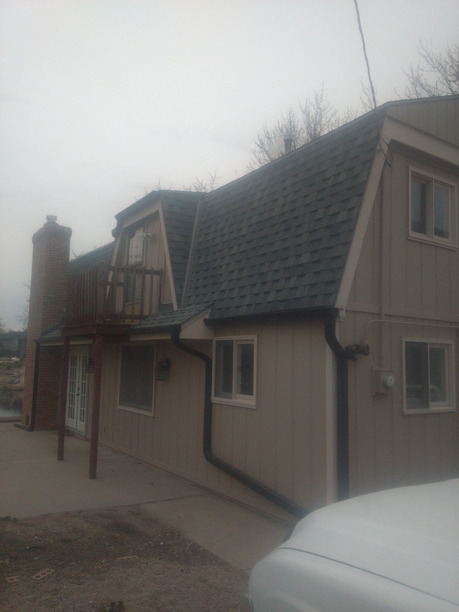 A white truck is parked in front of a house with a blue roof.