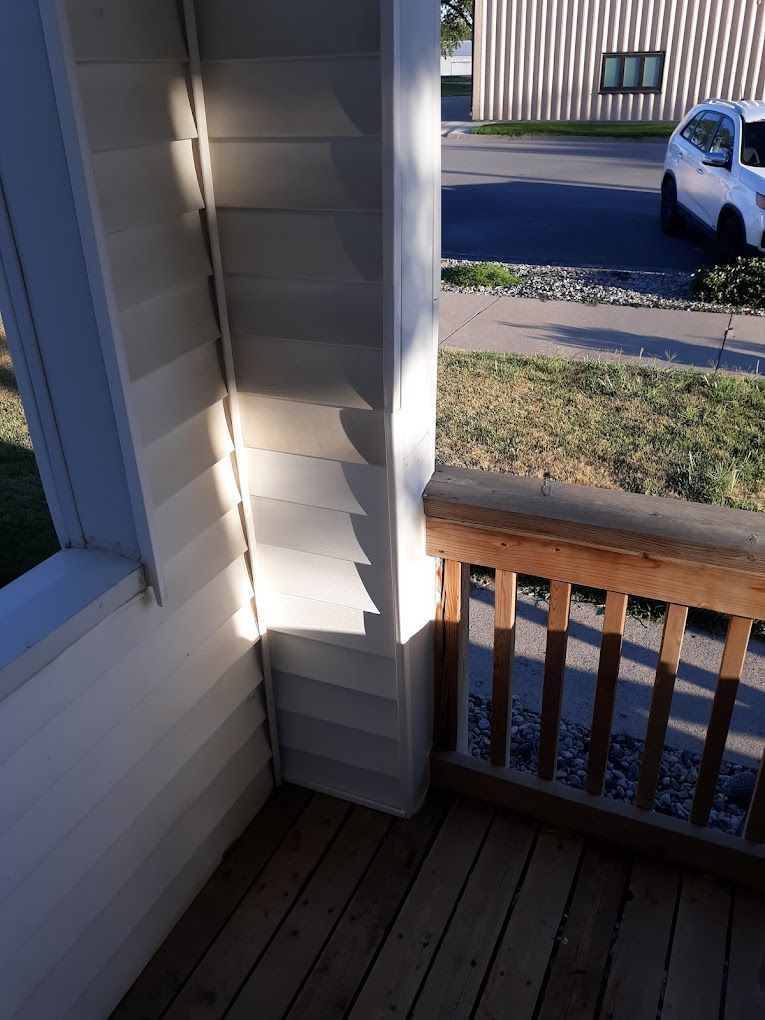 A white car is parked on the side of the road in front of a house.