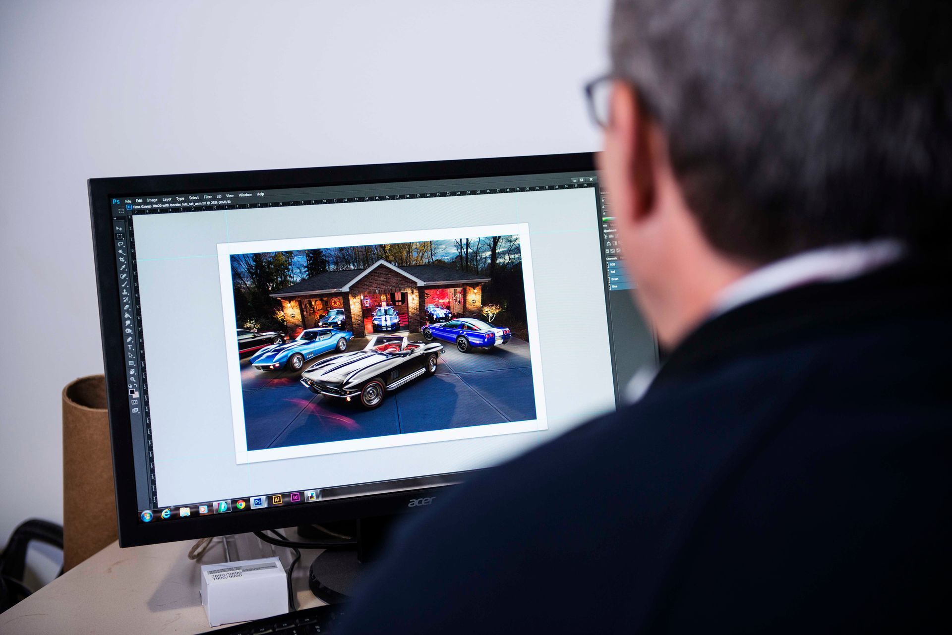Man working on computer with car photo.