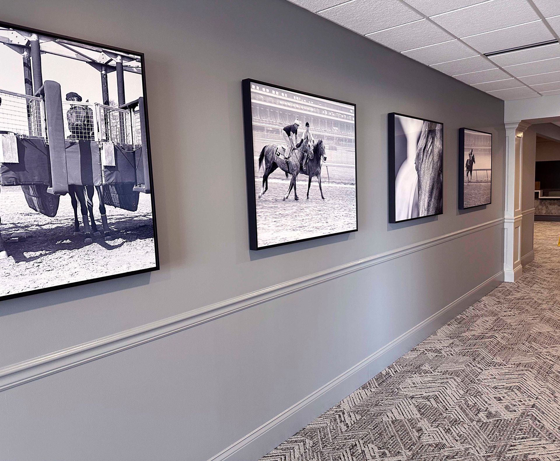 Hallway with black and white framed artwork on gray wall, above decorative molding.