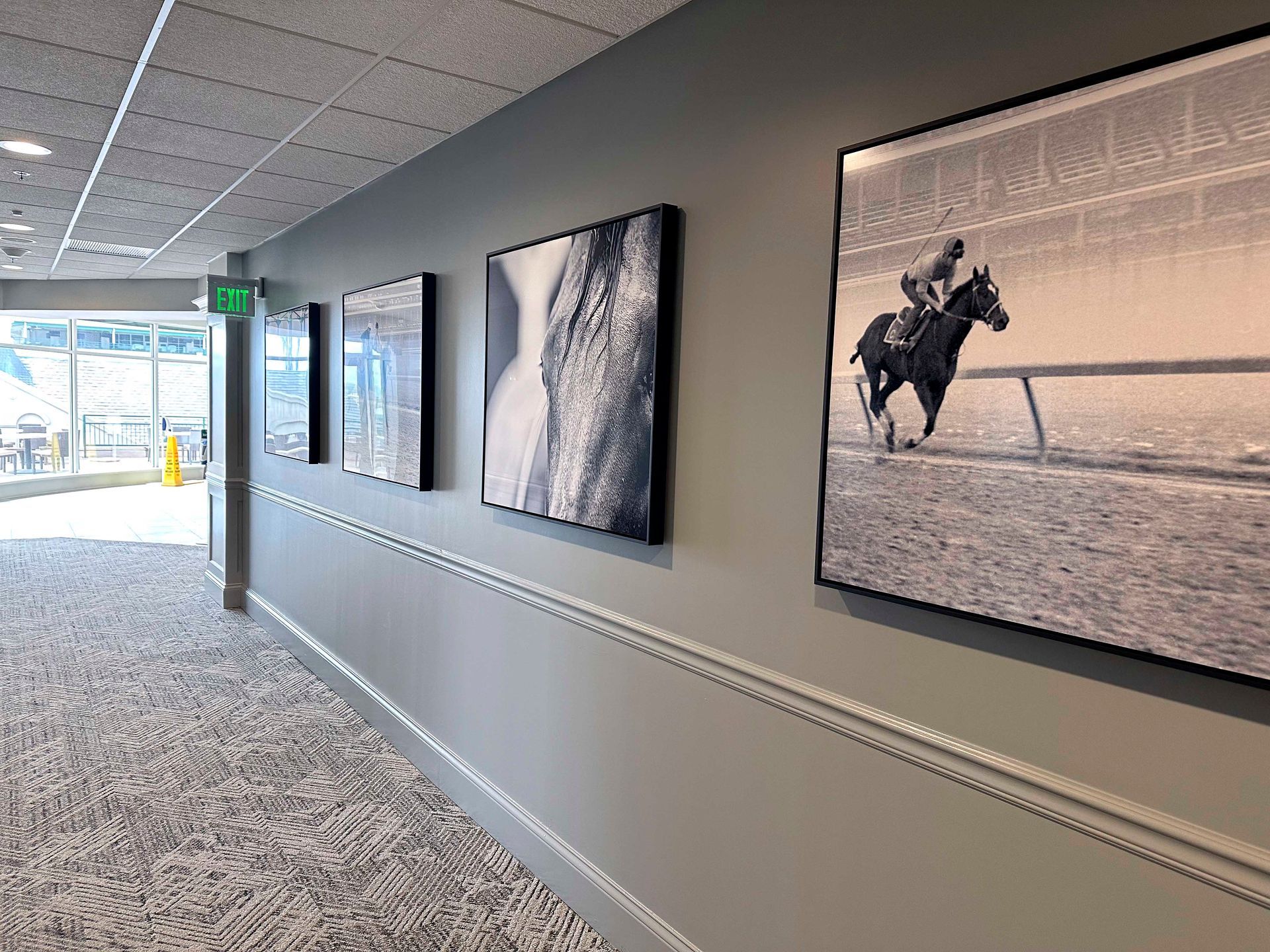 Hallway with framed black and white photos on a gray wall, leading to an open doorway.