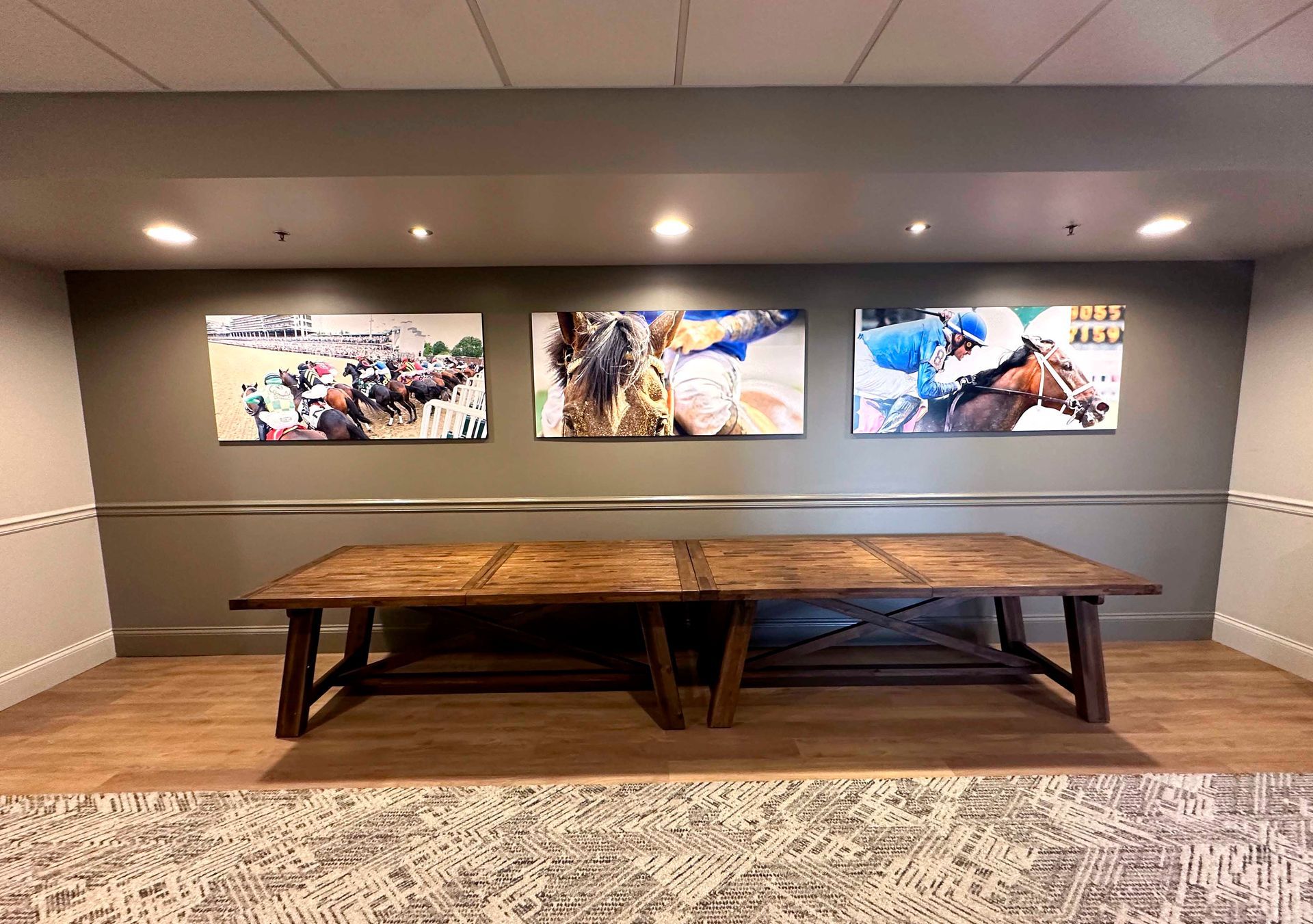 Hallway with a long wooden table beneath three framed horse racing photos.