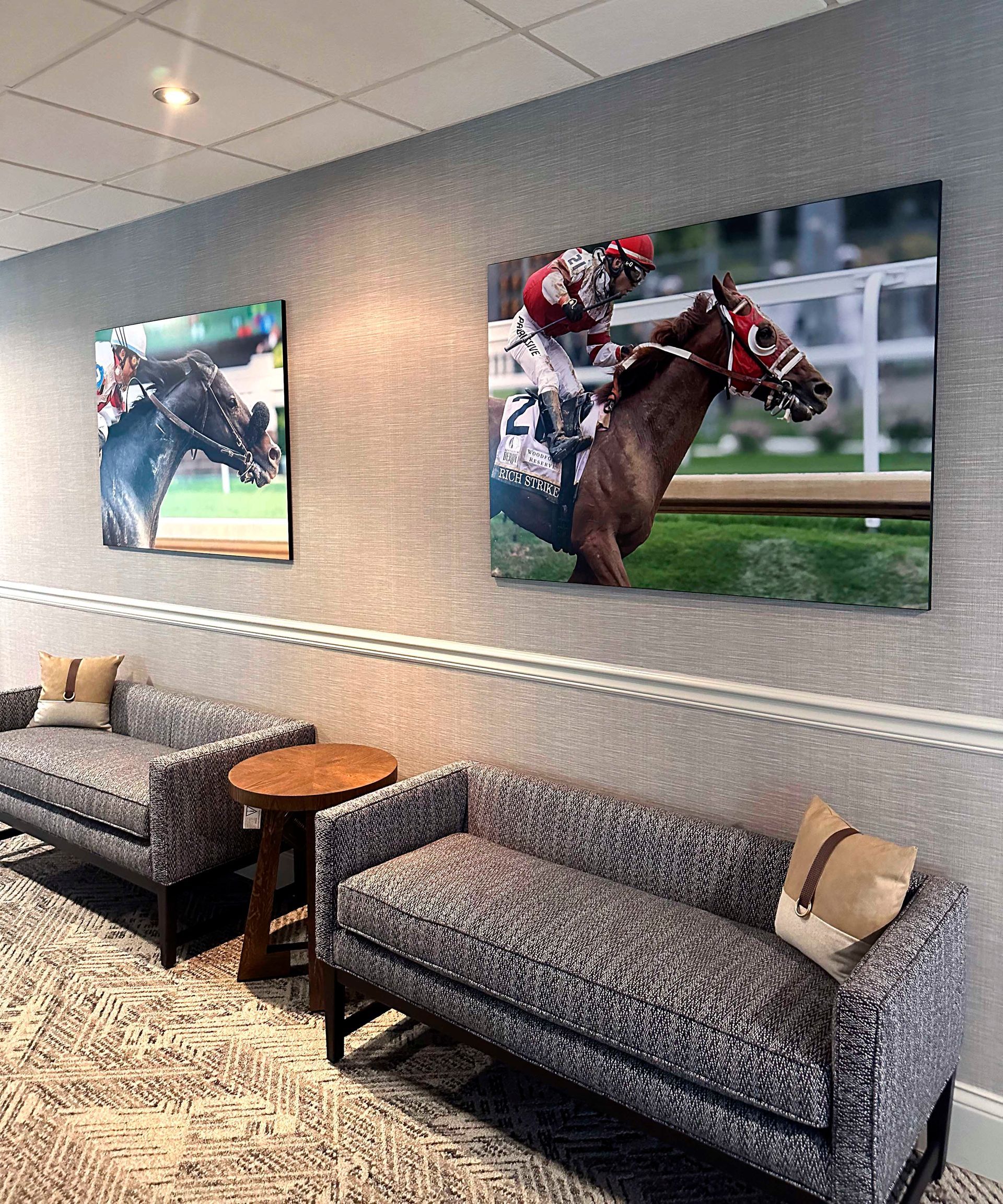 Two couches with horse racing photos on textured wall.