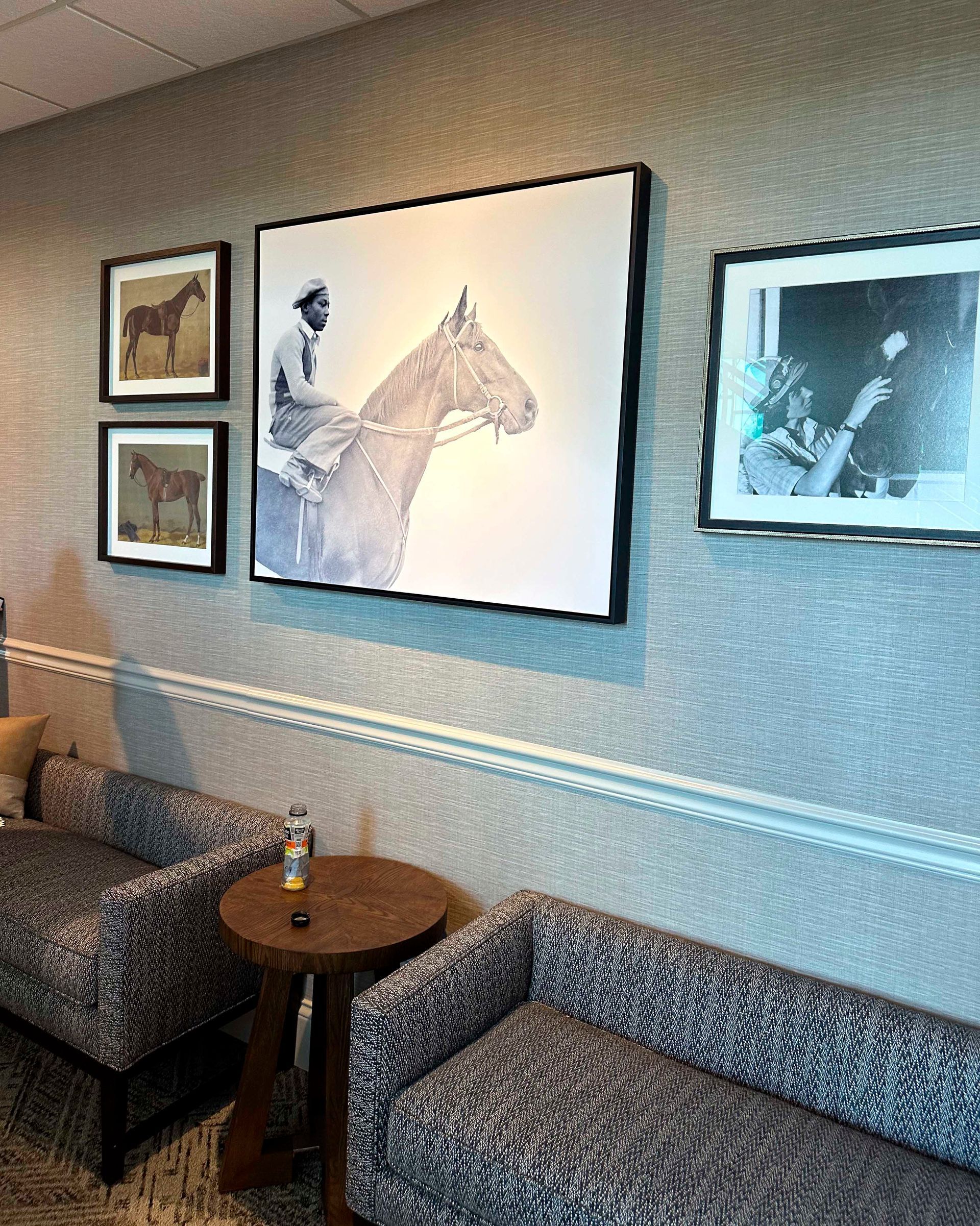 A room with horse-themed art. Two patterned sofas face a small table.