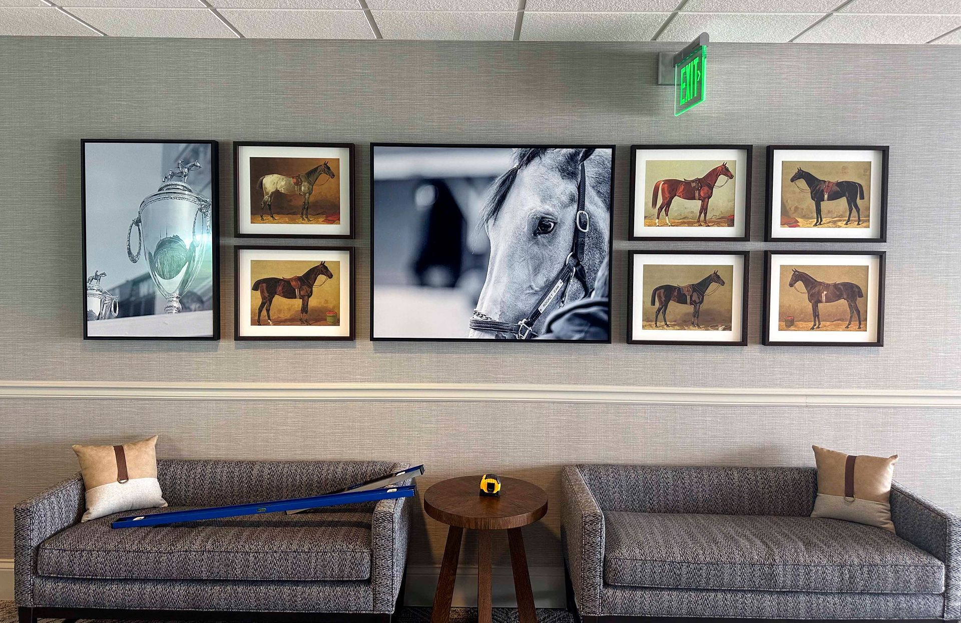 Lounge area with horse photos on a wall above two patterned couches. A small table sits between the couches.