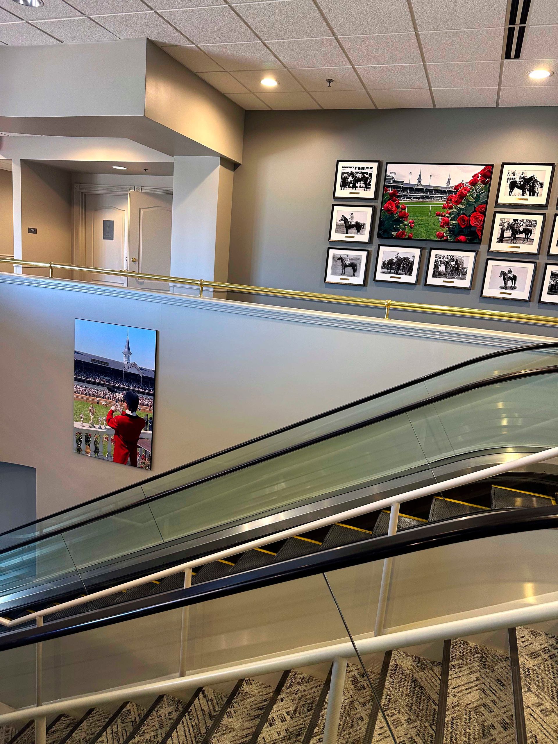 Escalator with wall art; a horse racing theme in an indoor setting.
