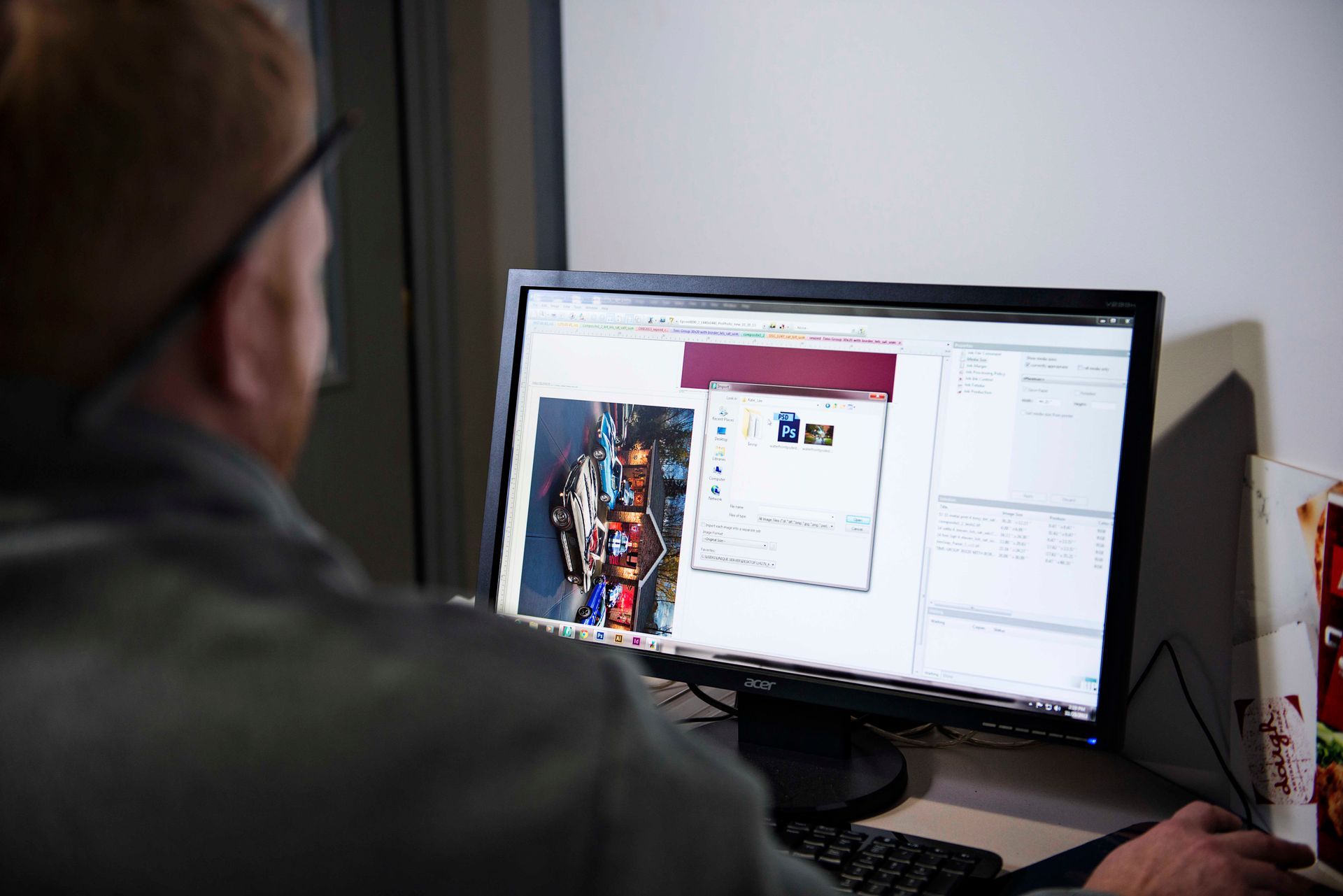 Person with glasses working at a computer, looking at a photo on the screen.