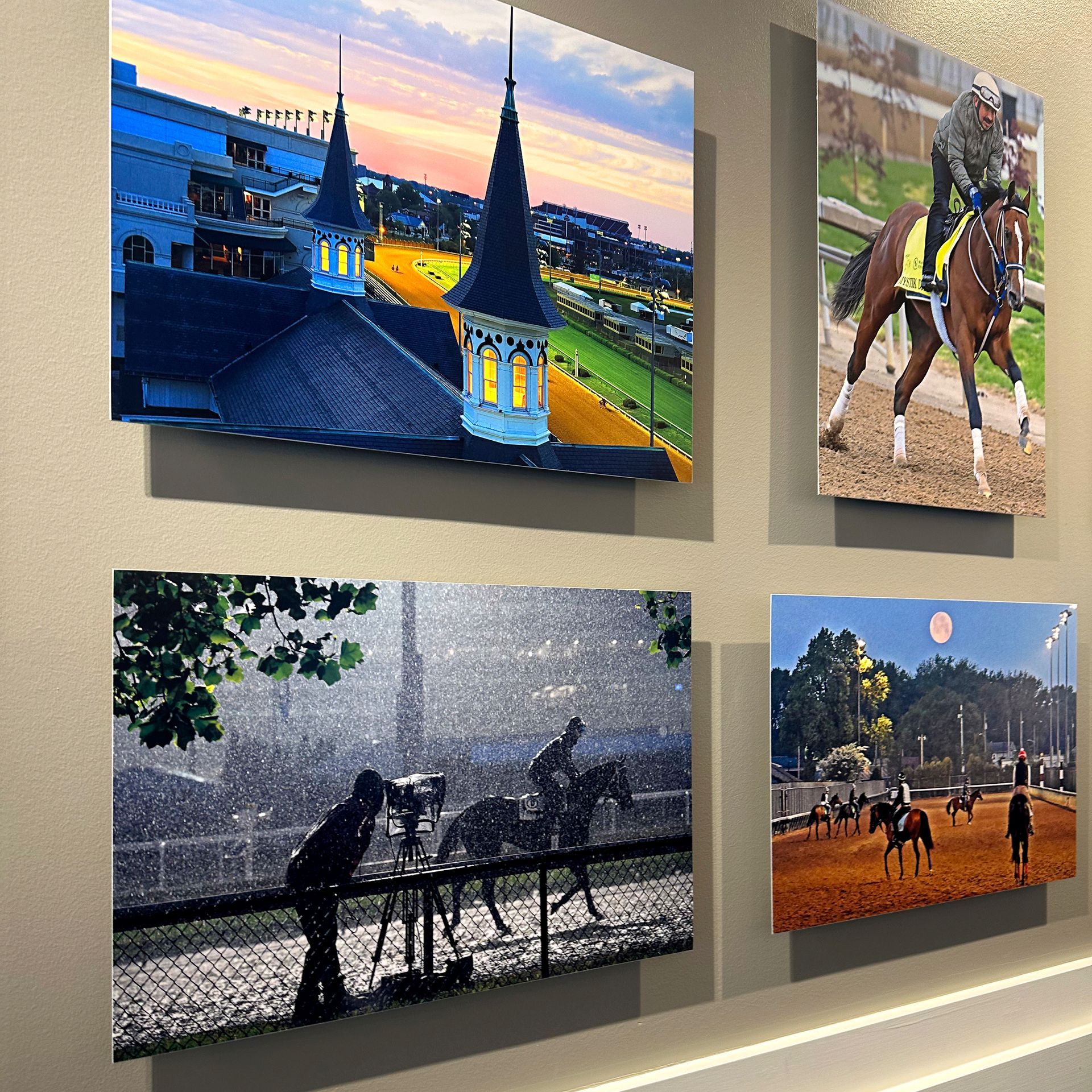 Four framed horse racing photos on a wall: a track at dusk, horse training, riders in the rain, and horses on a red clay track.