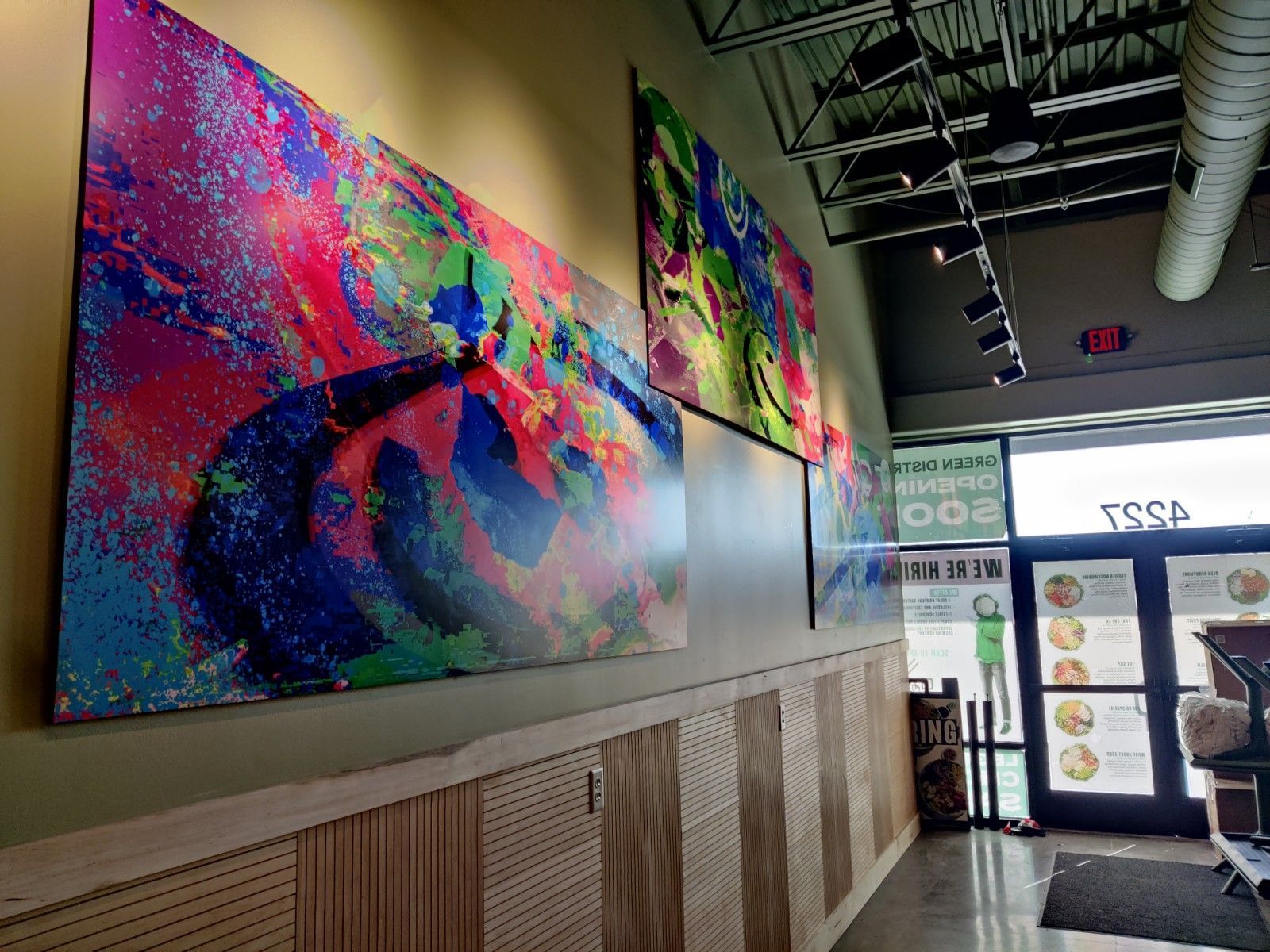 Colorful abstract art on a wall in a business, next to a doorway.