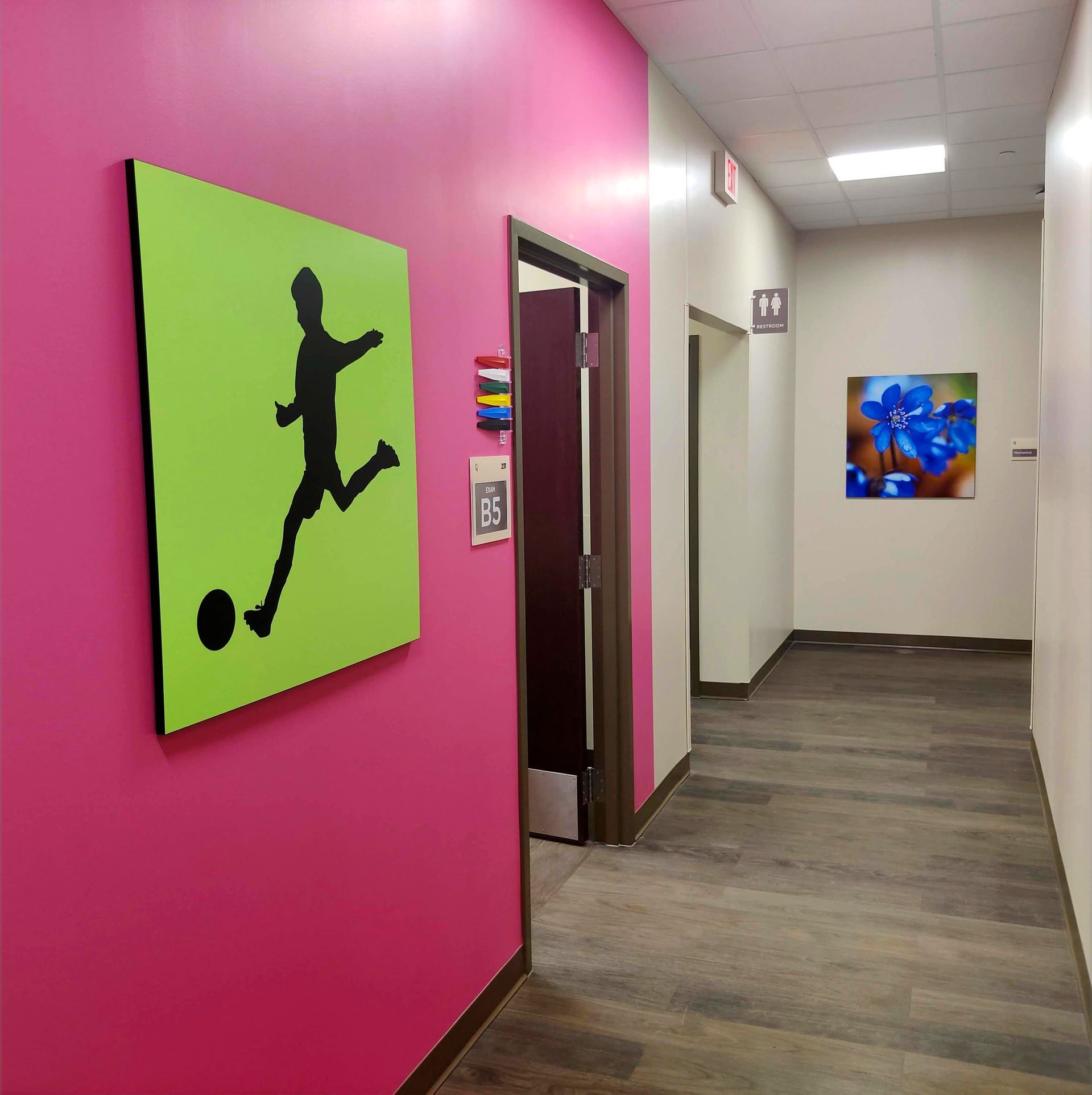 Hallway with pink and white walls, soccer art, and a partially open door.