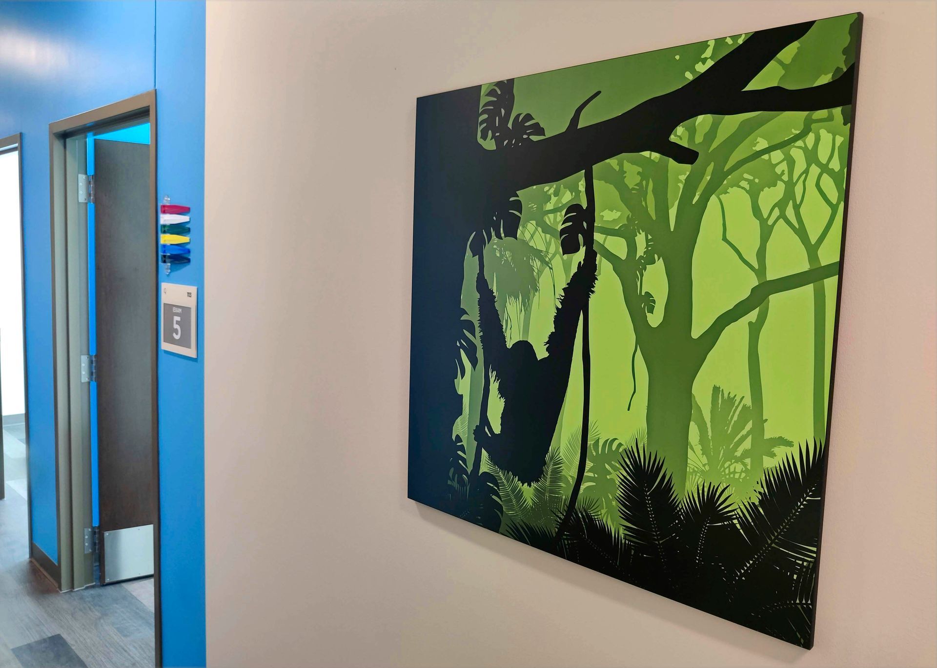 Hallway with a jungle-themed painting; a monkey hangs from a vine. Light and dark greens and blues.