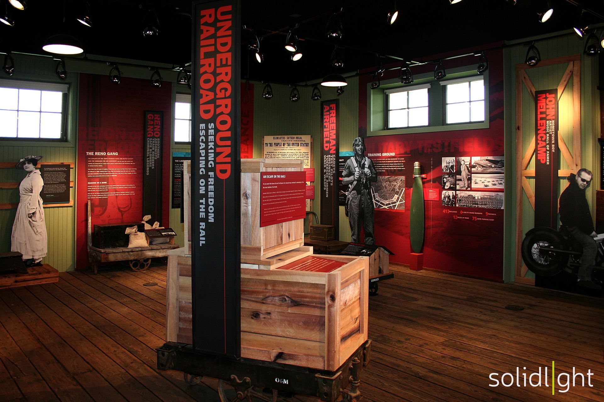 Museum exhibit about the Underground Railroad; wooden crates, red panels, historical photos, and a statue.